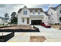 A charming two-story home features an attached garage, a driveway with a red car, and construction fencing at 6501 Burnette Flower Way, Raleigh, NC 27612