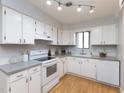 Well-lit kitchen featuring white cabinetry and modern appliances with a window view at 7353 Sandy Creek Dr, Raleigh, NC 27614