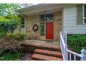 Inviting front entrance with a red door, brick steps, and a decorative wreath accenting the brick facade at 803 Churchill Dr, Chapel Hill, NC 27517