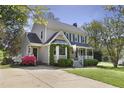 Inviting two-story home with a covered porch, beautiful bay window, a driveway, and colorful azalea bushes at 8608 Cheerful Ct, Raleigh, NC 27615