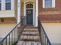 Inviting front entrance with a charming wreath, 'Home Sweet Home' sign, and brick stairs at 8722 Macedonia Lake Dr, Cary, NC 27518