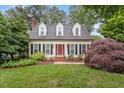 Charming home with a manicured lawn, red door, and dormer windows at 912 Salem Woods Dr, Raleigh, NC 27615