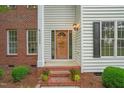 Inviting front entrance showcasing a wood door, brick steps with plants, and decorative accents at 1005 Barmkin Pl, Knightdale, NC 27545