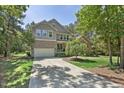 Beautiful home featuring a spacious driveway, attached garage, and lush green lawn surrounded by mature trees at 1009 Blue Larkspur Ave, Wake Forest, NC 27587