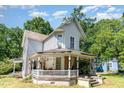 Angle view of a two-story home with a charming front porch surrounded by mature trees at 110 E Church St, Creedmoor, NC 27522