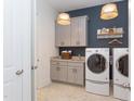 Well-lit laundry room featuring modern washer and dryer, storage cabinets, and stylish pendant lights at 1412 Auman Rd, Raleigh, NC 27603