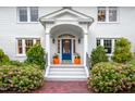 Inviting front entrance with a vibrant blue door, white pillars, and colorful flower pots at 1519 Hermitage Ct, Durham, NC 27707