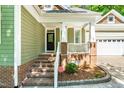 Inviting front porch with brick steps, white railings and columns and decorative front door at 166 Daffodil Ln, Clayton, NC 27527