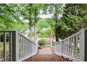 Pathway with white railings and brick stairs leading to a charming home with trees and an American flag at 204 Muirfield Ln, Clayton, NC 27527