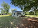 Quaint home with a black metal roof, manicured lawn, and mature trees at 317 Brewer Rd, Louisburg, NC 27549