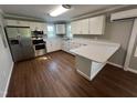 Bright kitchen with white cabinets, stainless steel appliances, and a breakfast bar on hardwood floors at 317 Brewer Rd, Louisburg, NC 27549