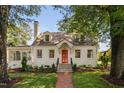 Charming white home with a brick walkway and a red front door surrounded by mature trees at 3210 Merriman Ave, Raleigh, NC 27607