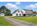Two-story white farmhouse with black shutters and lush green lawn, next to long private driveway at 4600 Smithfield Rd, Wendell, NC 27591