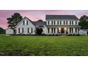 Charming two-story white farmhouse with black shutters and a lush green lawn, seen at twilight at 4600 Smithfield Rd, Wendell, NC 27591