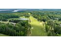 Scenic aerial view showcasing the golf course, a tranquil pond, and surrounding lush greenery at 671 Bear Tree Crk, Chapel Hill, NC 27517