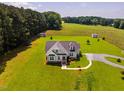 Exterior elevation of a charming, light-gray home featuring well-manicured lawn and gravel driveway on expansive acreage at 6916 Morrow Mill Road, Chapel Hill, NC 27516