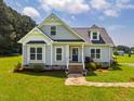 Charming front exterior of a light-gray home featuring a well-manicured lawn, blue front door and stone walkway at 6916 Morrow Mill Road, Chapel Hill, NC 27516
