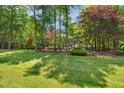 Sprawling backyard with green lawn and a two-story brick house surrounded by mature trees at 7309 New Forest Ln, Wake Forest, NC 27587