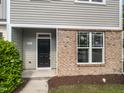Inviting townhouse entrance with a black front door and brick detailing, showcasing curb appeal at 8891 Commons Townes Dr, Raleigh, NC 27616