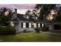 Charming home with manicured lawn, classic white facade, black shutters, and a cozy, lit front porch at dusk at 1001 N Orange Ave, Dunn, NC 28334