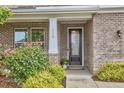 A welcoming front entrance features a glass paneled door, brick facade, with meticulously trimmed landscaping at 112 Filigree Way, Durham, NC 27713