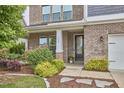 Inviting front entrance with a brick facade, manicured landscaping, and a glimpse of the glass paneled front door at 112 Filigree Way, Durham, NC 27713