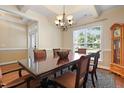 This dining room is illuminated by a chandelier, and features a table with seating for six and sunlit view at 13 Nettletree Creek Ct, Youngsville, NC 27596