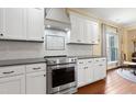 Well-appointed kitchen featuring white cabinets, granite countertops, stainless steel appliances, and stylish backsplash at 13 Nettletree Creek Ct, Youngsville, NC 27596