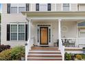 Inviting front porch with wood decking, white railings, and decorative columns leading to the front door at 1480 Big Leaf Loop, Apex, NC 27502