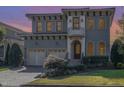 Twilight view of a two-story stucco home with arched windows, beautiful landscaping, and a two-car garage at 15 Treviso Pl, Durham, NC 27707