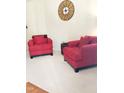 Comfortable living room with bright red armchairs, neutral carpet, and decorative wall clock at 1633 Snow Mass Way, Durham, NC 27713