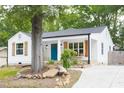Quaint white cottage with stone foundation, shutters, blue front door, and rock-lined flowerbeds at 212 E Rockway St, Durham, NC 27704
