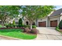 Serene home exterior with lush greenery, manicured lawn, stone accents, and a spacious driveway leading to the attached garage at 603 Hawks Ridge Ct, Apex, NC 27539