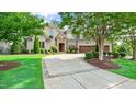 Beautifully landscaped home with mature trees, a stone entrance, circular driveway, and a three-car garage, offering curb appeal at 603 Hawks Ridge Ct, Apex, NC 27539