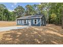 Quaint blue one-story home with a concrete driveway and lush green surroundings at 679 Jasmine Rd, Fuquay Varina, NC 27526