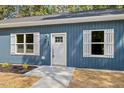 Close-up of a blue home's entrance with white shutters, a charming doorway, and a manicured lawn at 679 Jasmine Rd, Fuquay Varina, NC 27526
