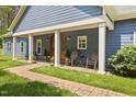 Inviting covered front porch featuring rocking chairs, lush greenery, and a charming brick walkway, perfect for relaxation at 741 Sinai Cir, Hillsborough, NC 27278