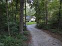 Charming home nestled among trees with a gravel driveway leading to the house at 8812 Valley Hill Ct, Apex, NC 27539