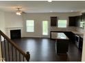 Open-concept living area with dark wood floors, fireplace, ceiling fan, and a view of the kitchen at 1249 Turkey Trot Rd, Wendell, NC 27591