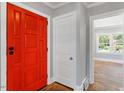 Bright entryway featuring a bold red front door, hardwood floors, and freshly painted walls at 134 Nelson St, Durham, NC 27707