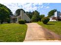 View of the house and long driveway, surrounded by a lush green yard and mature trees, offers privacy and space at 200 Steeple Rd, Holly Springs, NC 27540