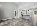 Open concept living room with vaulted ceiling and vinyl plank flooring next to a gray and white kitchen at 2921 Wall Store Rd, Garner, NC 27529