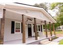 Charming front porch with dark wooden columns, ceiling fans, black door, and meticulously landscaped flower beds at 3030 Forrester St, Durham, NC 27704