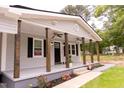 Inviting front porch featuring wooden columns, ceiling fans, black shutters, and a black front door at 3030 Forrester St, Durham, NC 27704