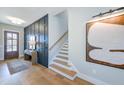 Chic foyer with wood floors, paneled wall, a staircase, and modern artwork displayed above a console table at 361 Murray Grey Ln, Wake Forest, NC 27587