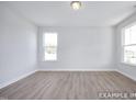 Bright bedroom featuring wood-look floors and two windows providing natural light at 436 Longleaf Glen Lane, Zebulon, NC 27597
