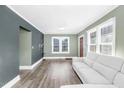 Open living room features hardwood floors, a gray sofa, and abundant natural light through large windows at 507 S Mebane St, Burlington, NC 27215