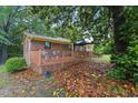 A charming brick home features a cozy deck surrounded by mature trees and a yard covered in colorful fall leaves at 5932 Johnson Pond Rd, Fuquay Varina, NC 27526