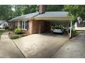 Long paved driveway leading to carport attached to brick house with an exterior door at 609 Malone Ct, Burlington, NC 27215
