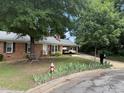 View of brick home with mature shade trees, black shutters, and a covered carport at 609 Malone Ct, Burlington, NC 27215
